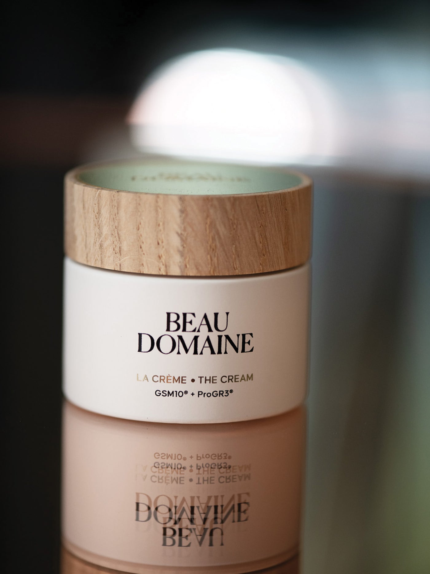 Beau Domaine cream jar with wooden lid on a blurred background