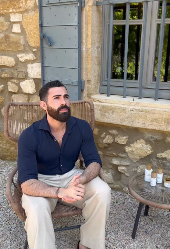 Man sitting on a chair outdoors with a stone building and window in the background