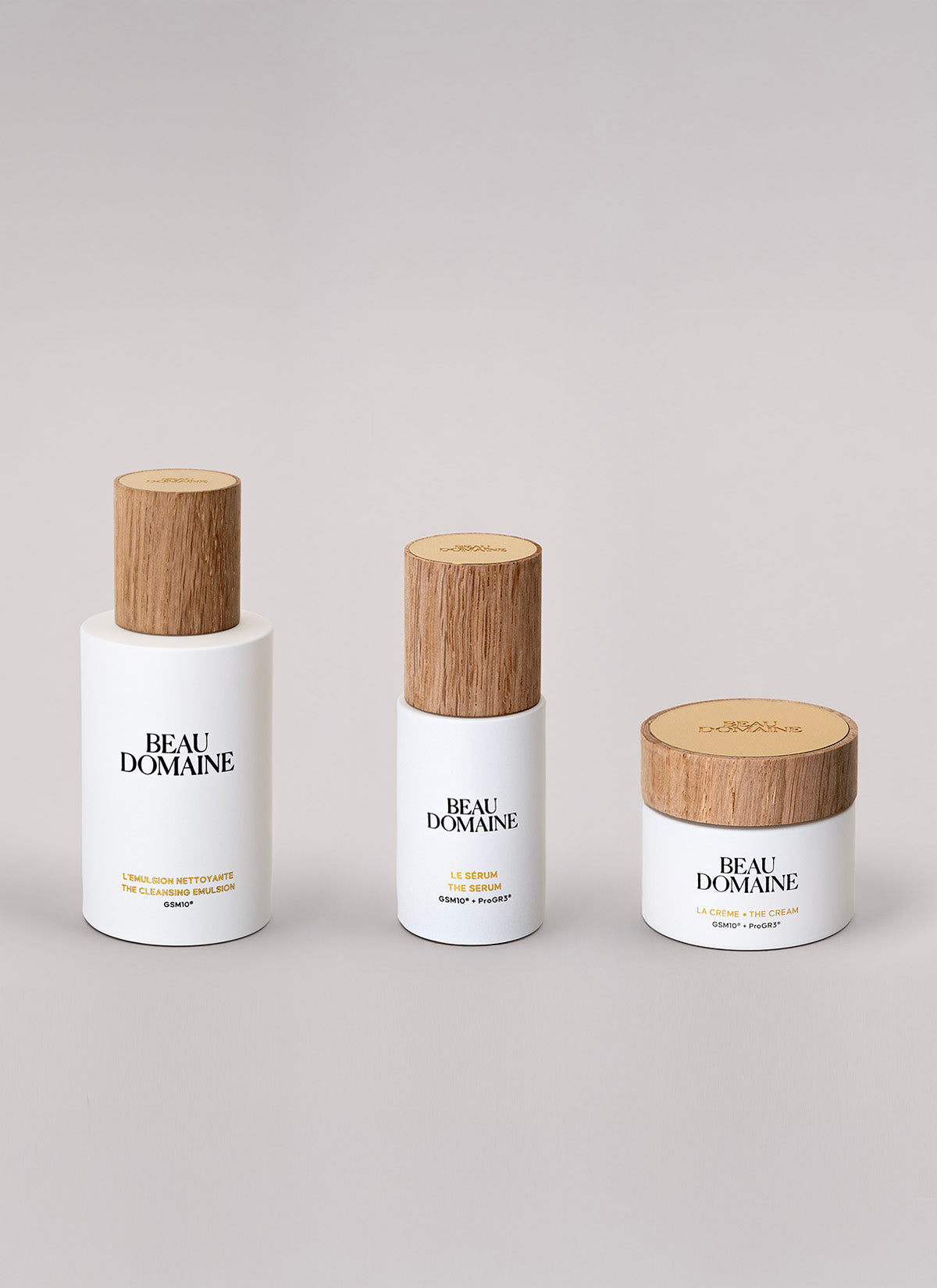 Three 'Beau Domaine' skincare products with wooden caps on a light gray background